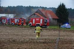 Strażak OSP dojechał do pożaru w Podkosaczach i biegnie przez pola, aby ratować dobytek innych.