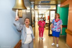 Małgorzata Kuczewska ogłasza pokonanie raka uderzając w Dzwon Zwycięzcy przed wejściem do oddziału onkologicznego w szpitalu w Łmży.